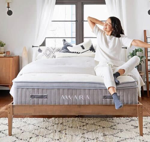 In this image, a woman is relaxing on the edge of the Awara Natural Latex Hybrid Mattress, which contains natural latex and pocket coils. Natural latex is chemical free and hypoallergenic.