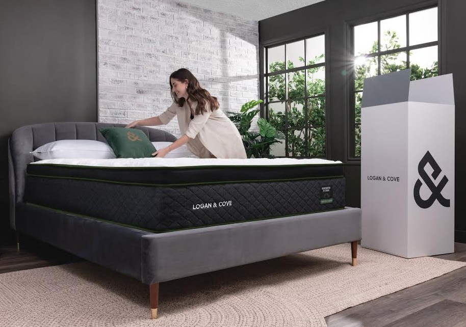 the logan and cove choice mattress shown with the shipping box, measuring approximately  42" tall, and 22" wide and deep. A woman is positioning pillows at the head of the mattress in a sunny, well lit bedroom. A solid best matress in Canada option.
