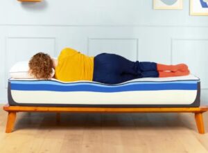 Teen lying sideways on the Nectar Mattress, showing how her body immerses on the mattress. The photo shows her hips and shoulders immersing deeper than other parts of her body.