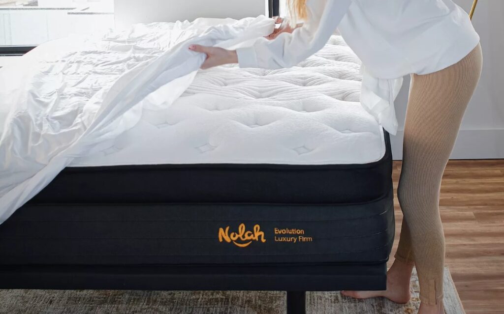nolah adjustable base fits discreetly underneath your nolah mattress. view of woman putting sheets on nolah evolution mattress with ajdustable base underneath.
